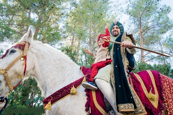 A majestic pose of the groom arriving at the wedding venue on a horse, depicting traditional grandeur.